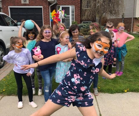 group of children with their faces painted, girl in foreground with a face painted like a fox